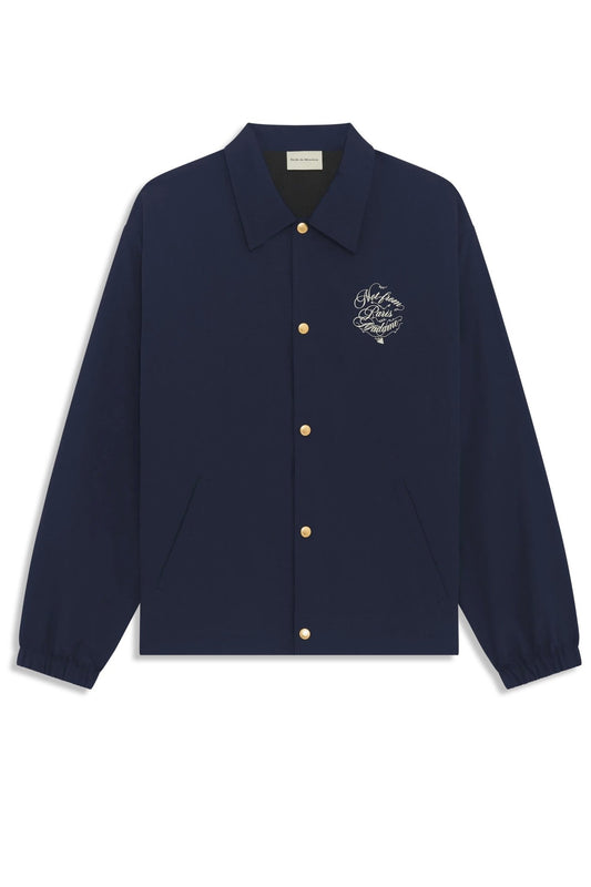 The Drôle de Monsieur F-JT209-PA012-Ny La Veste Navy is a navy ripstop jacket with a loose fit, gold buttons, embroidered chest text, a collar, and long sleeves.