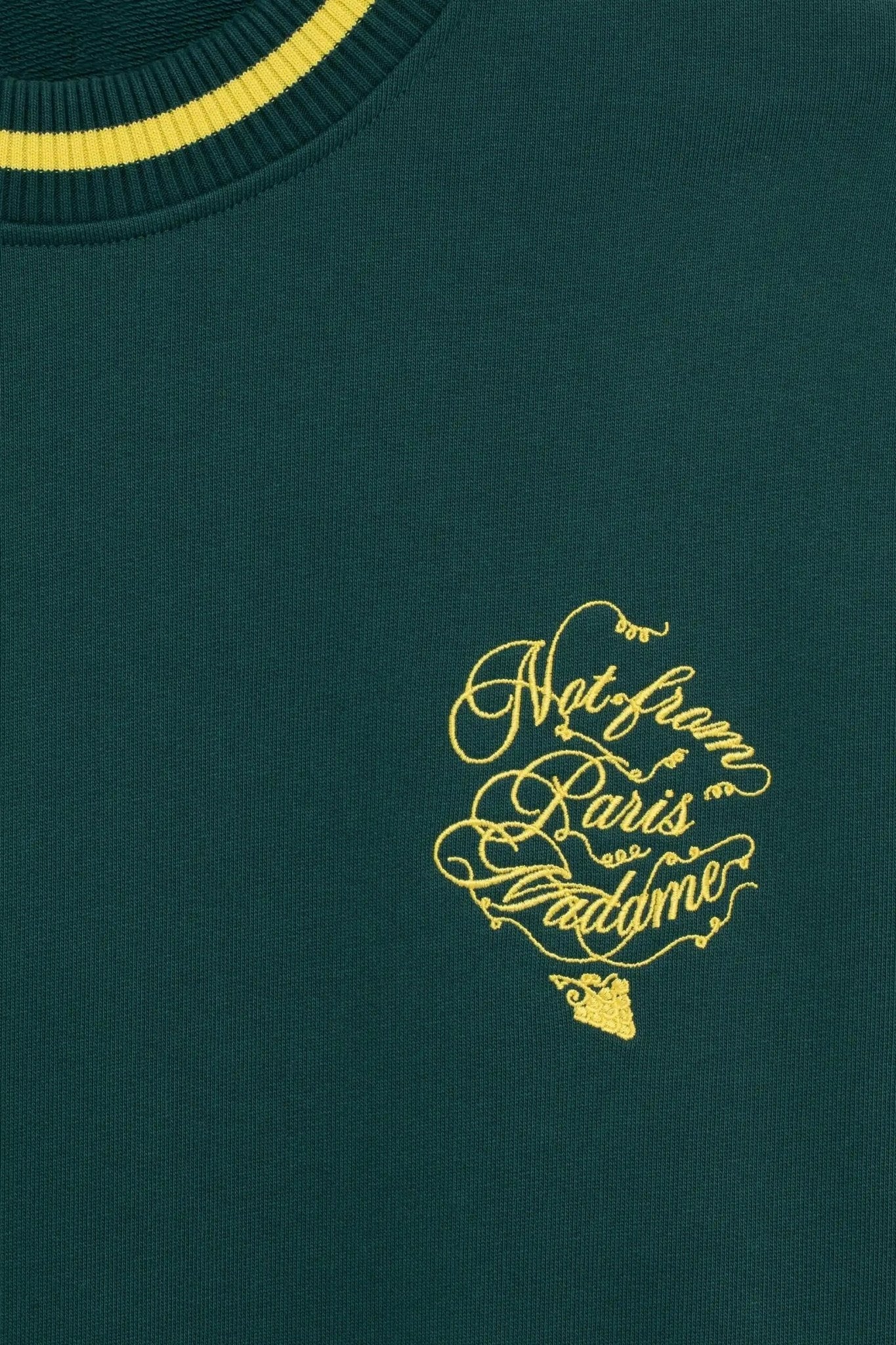 Close-up of Drôle de Monsieur F-SW156-CO127-Dgn Le Sweatshirt Green in French terry, featuring Slogan Vignes print with yellow "Not from Paris Madame" cursive embroidery.