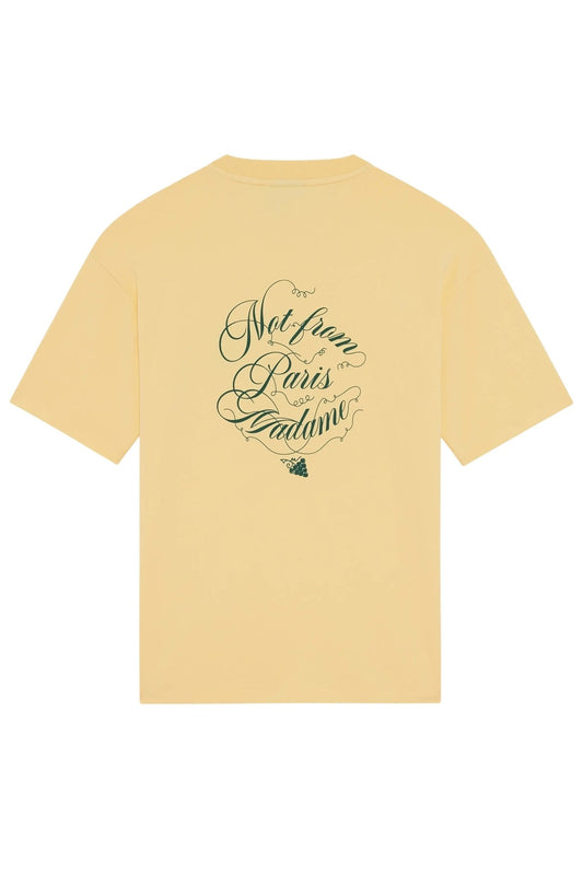 The Drôle de Monsieur F-TS226-CO002 Le T-shirt Banana is a stylish yellow cotton T-shirt with elegant green script on the back that says "Not from Paris Madame" above a chic grape graphic, combining comfort and sophistication.