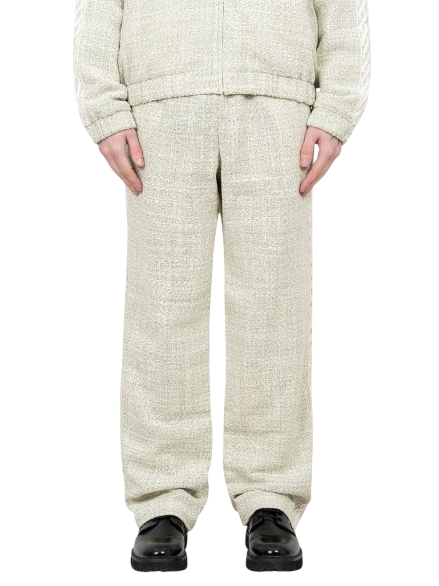 A person stands with arms relaxed, wearing Drôle de Monsieur G-BP183-CO186-LGN Pantalon Tweed Grn pants and a matching jacket, paired with black shoes.