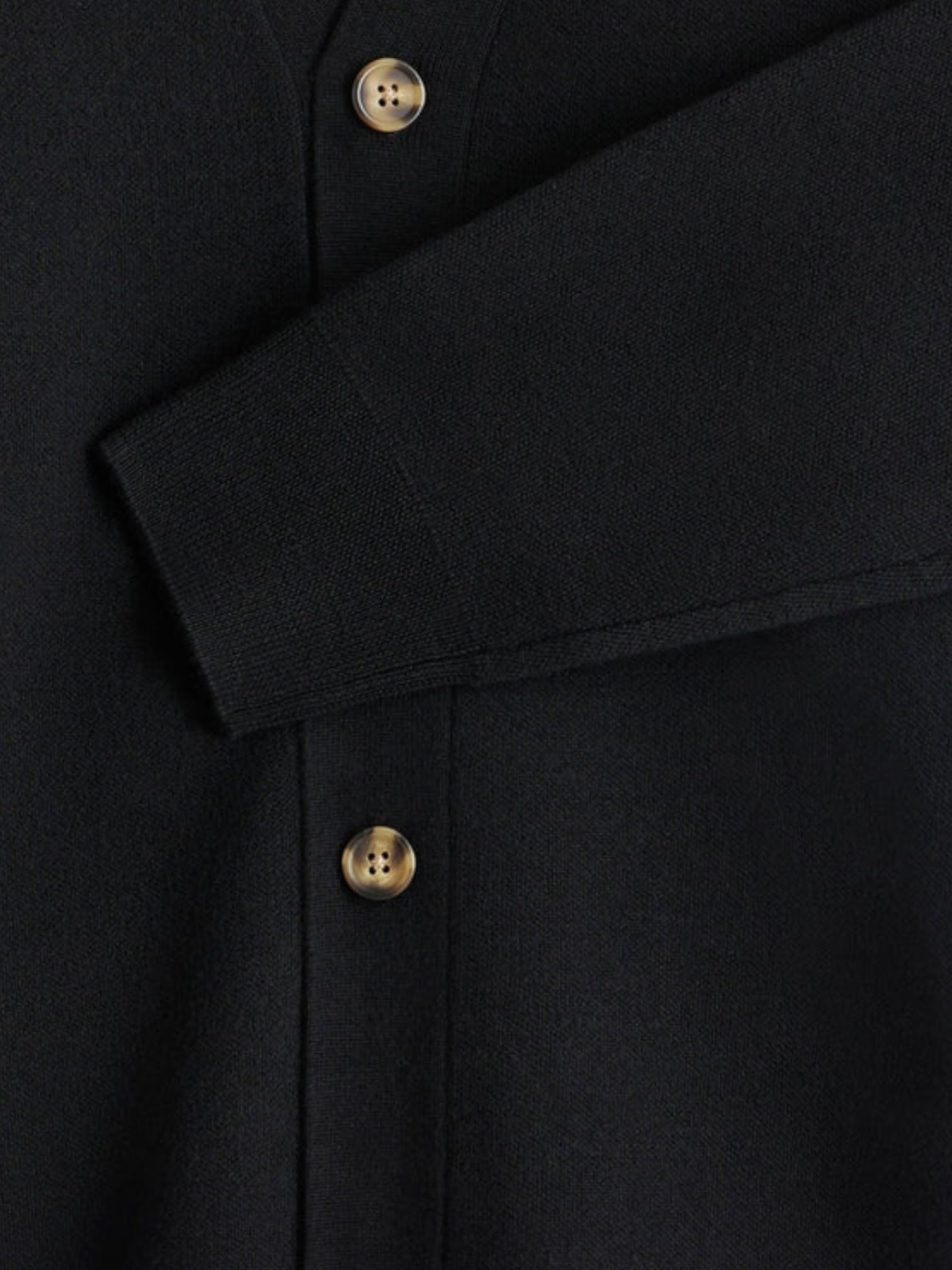 Close-up of the Drôle de Monsieur LE Cardigan Blk, featuring elegant embroidery, three beige buttons, and a diagonally folded sleeve.