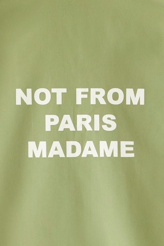 Text on a khaki cotton blend DROLE DE MONSIEUR shirt reading "not from paris madame", featuring a printed slogan. Made in Portugal.