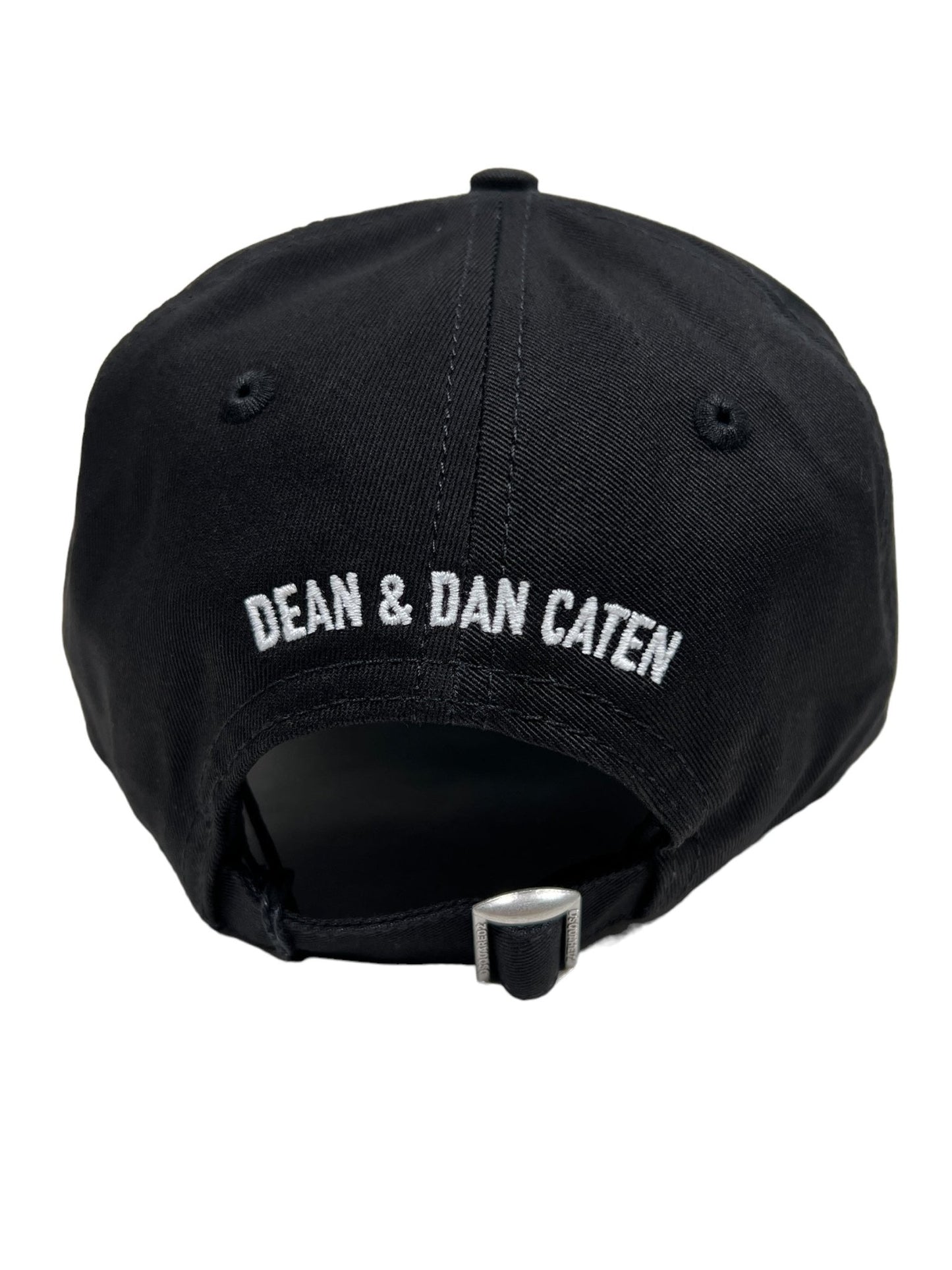 The back of the DSQUARED2 BCM0660 Technicolor baseball cap in black features "DEAN & DAN CATEN" embroidered in white uppercase letters above an adjustable strap with a metal buckle.