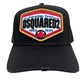 The DSQUARED2 BCM0763 Logo Baseball Cap in black is a stylish accessory featuring a vibrant embroidered patch on the front that reads "Canadian Twins, DSQUARED2, 1964 - 1995" along with a red maple leaf logo. The cap is designed with an adjustable strap to ensure a perfect fit.