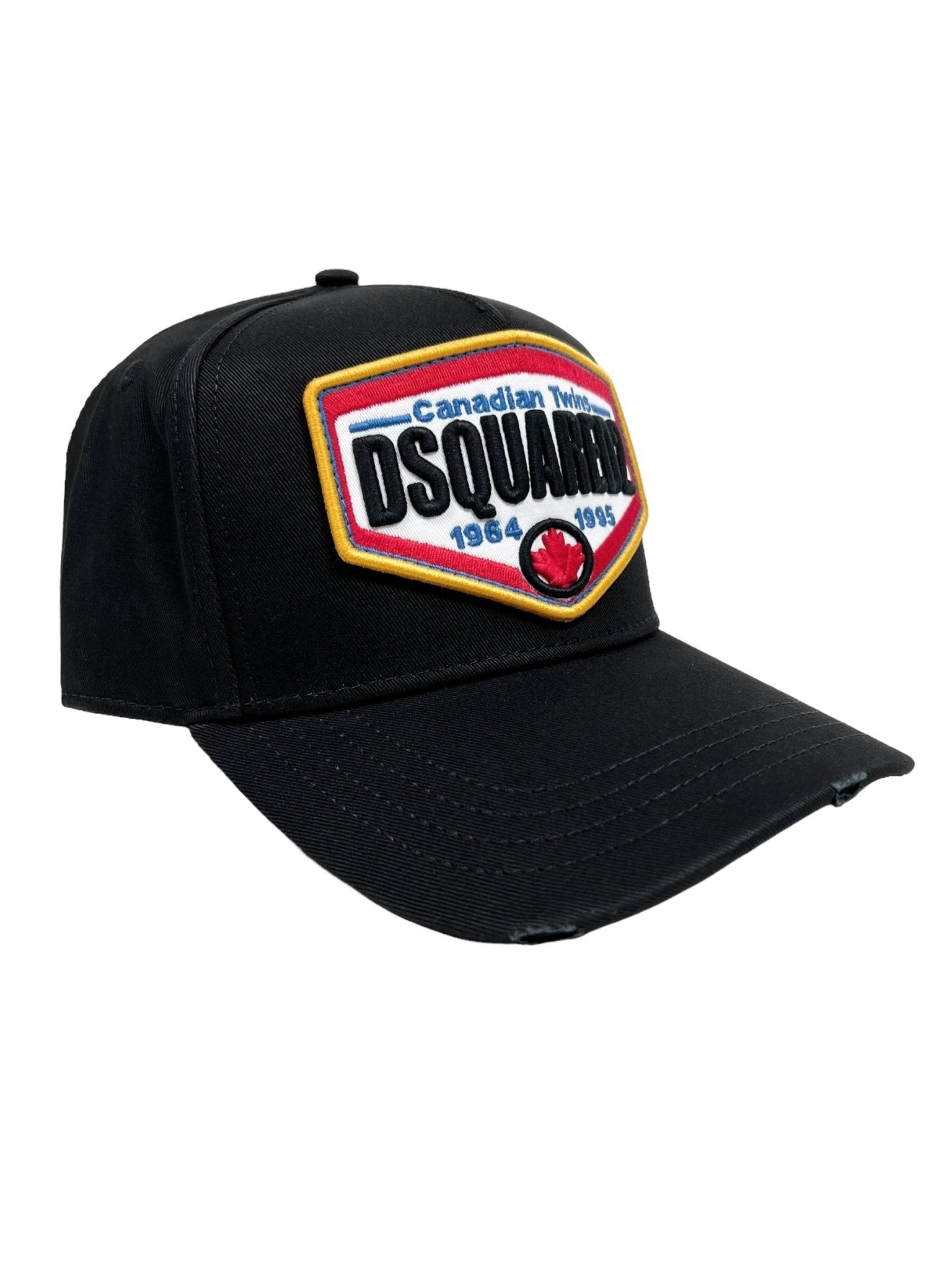 The DSQUARED2 BCM0763 Logo Baseball Cap Col.2124 is a black Canada tribute cap featuring a colorful "DSQUARED2" logo patch with "Canadian Twins 1964-1995" prominently embroidered on the front. Made from 100% cotton, it also has an adjustable strap for a perfect fit.