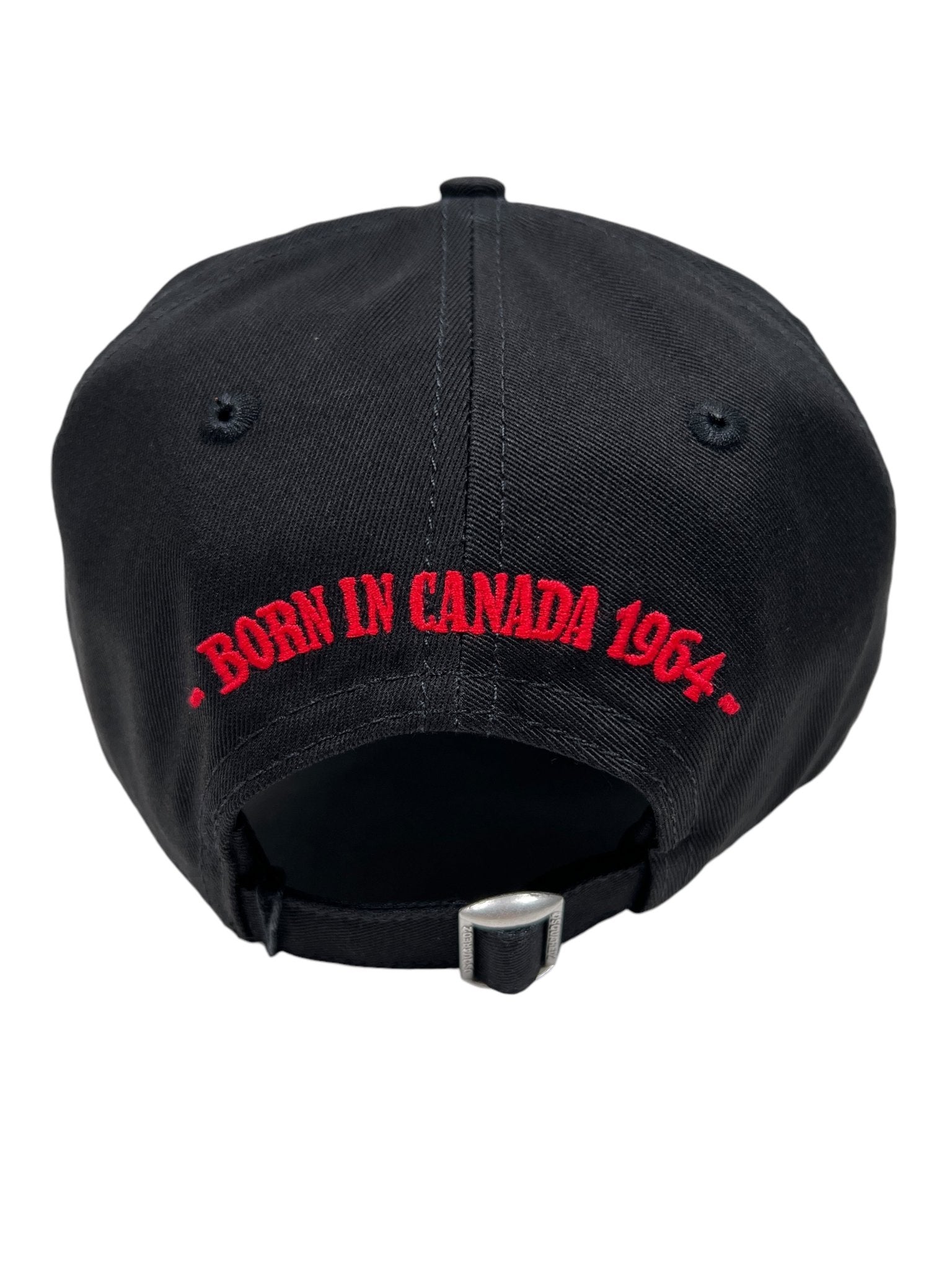 Discover the Dsquared2 BCM0847 cap in black cotton gabardine. It features red "BORN IN CANADA 1964" embroidery on the back, an adjustable strap with a metal clasp, and subtle distressed detailing for a modern touch.