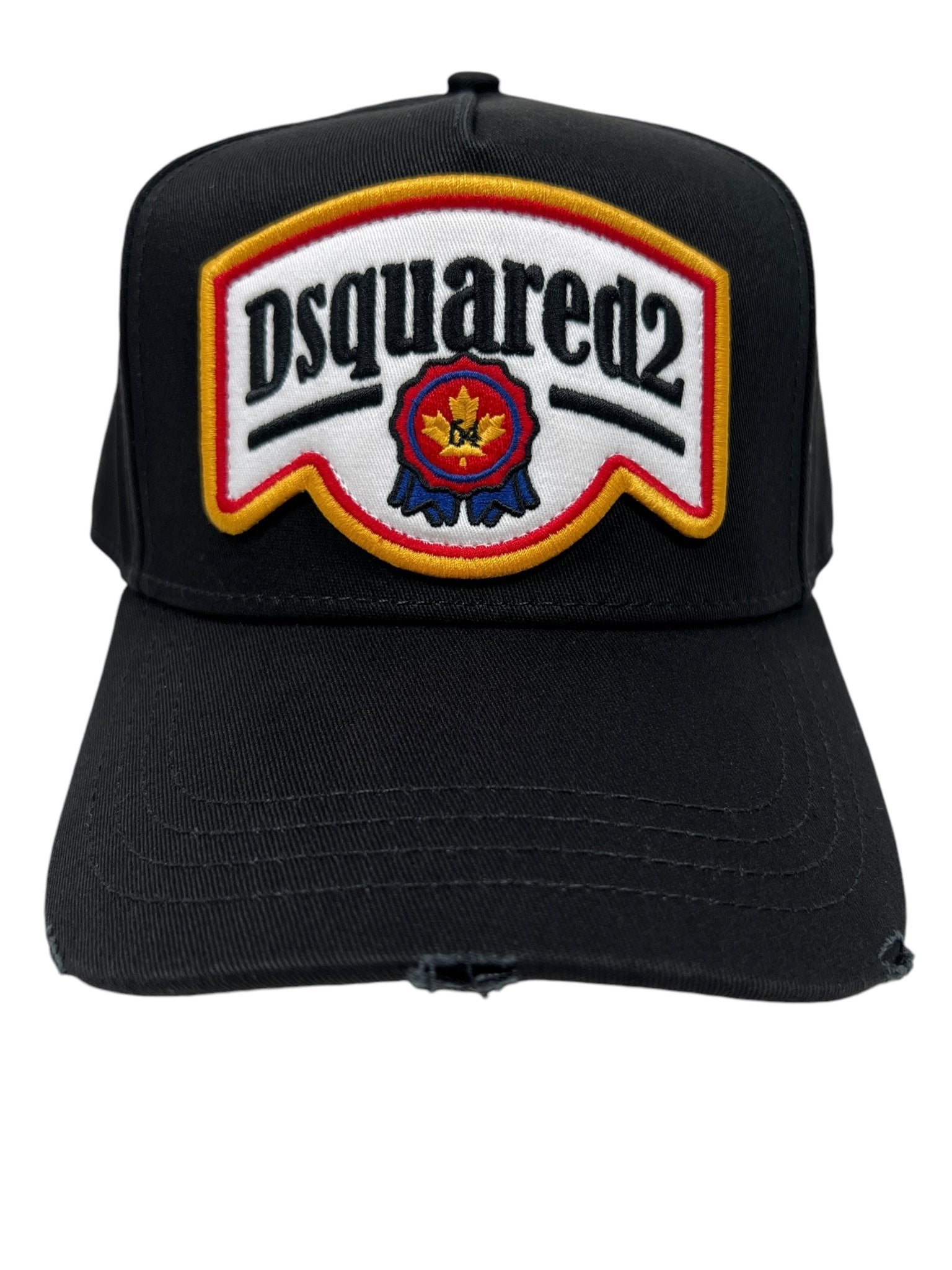 The DSQUARED2 BCM0847 Nero cap displays a "Dsquared2" logo patch with a maple leaf and mountain design. Made from cotton gabardine, it features subtle distressed details for a stylish, worn-in appearance.