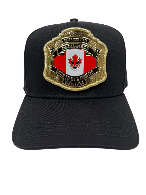 The DSQUARED2 BCM0903 Baseball Cap Gabardine-Nero is a black cotton gabardine cap featuring a bold gold and red embroidered crest with "OG Cuanebo, Born to Be a Fighter, Wrestling," perfect for those who embrace their daring spirit.