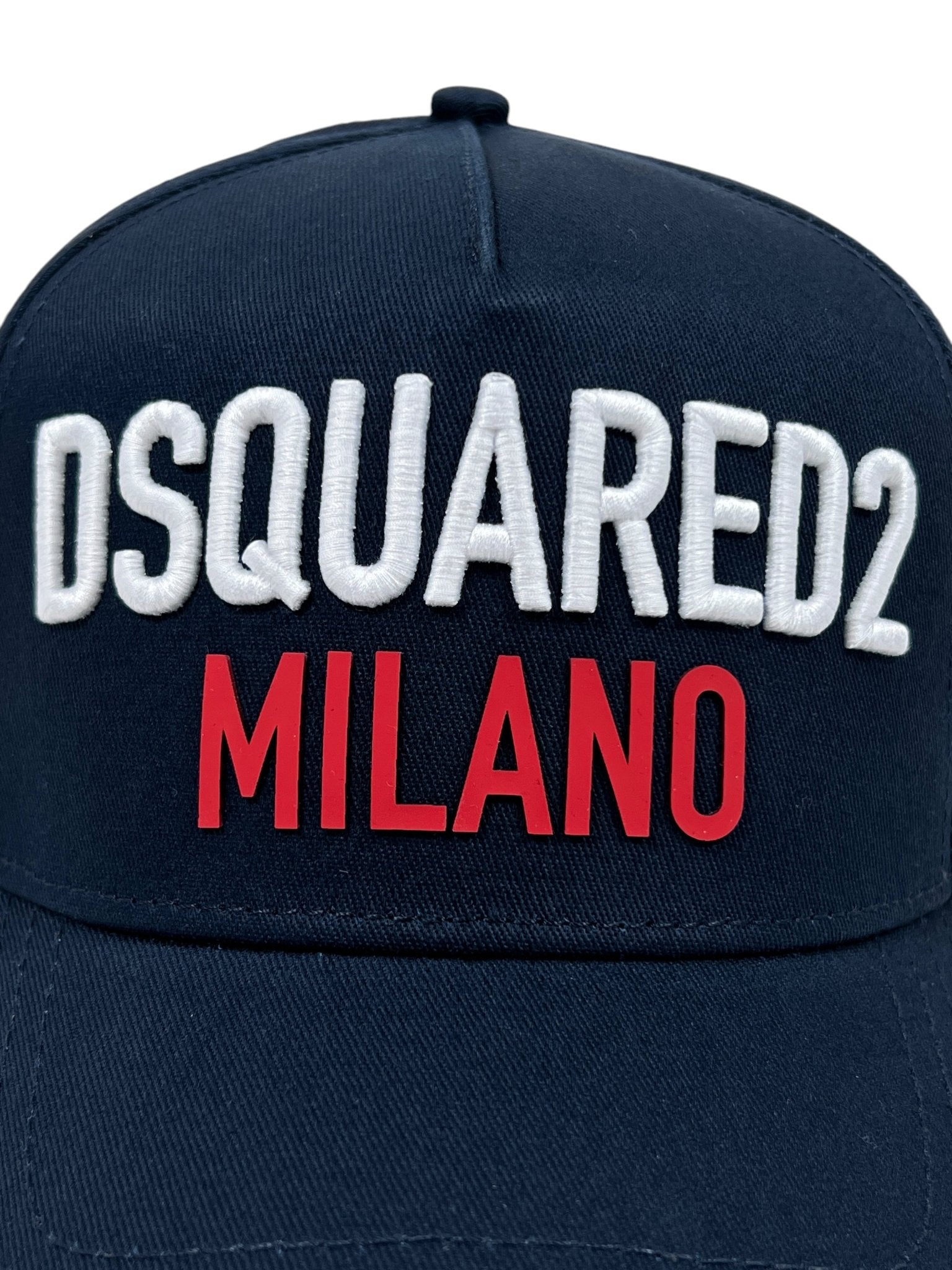 The DSQUARED2 BCM0917 Baseball Cap in navy features "DSQUARED2 MILANO" embroidered on the front in white and red letters, complete with an adjustable snapback for a perfect fit.