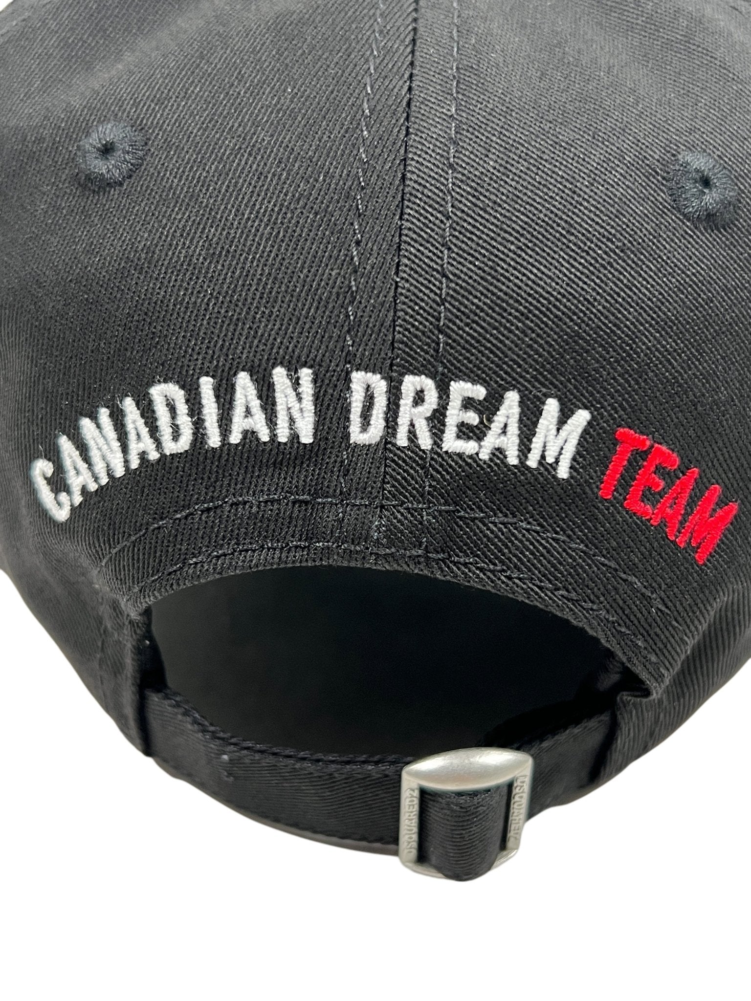 The Dsquared2 BCM0917 Baseball Cap Gabardine-Nero by DSQUARED2 showcases "CANADIAN DREAM TEAM" in bold white and red embroidery on premium cotton, offering an adjustable fit for ultimate comfort and style.