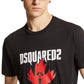 A person wearing a stylish black Dsquared2 S74Gd1307 Cool Fit Tee featuring a red maple leaf design, paired with a brown cap.