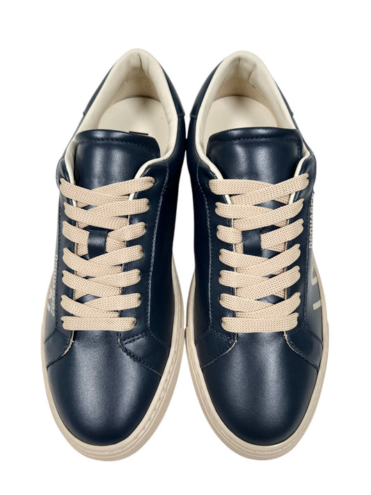 The Dsquared2 SNM0384 Cassetta Sneakers by DSQUARED2 feature a top-down view of navy blue shoes with cream laces and beige soles, crafted from premium leather, set against a white background.