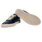 The DSQUARED2 SNM0384 Cassetta Sneakers in navy blue feature beige laces and soles, expertly crafted from premium leather, with one shoe standing upright and the other highlighting its textured sole.