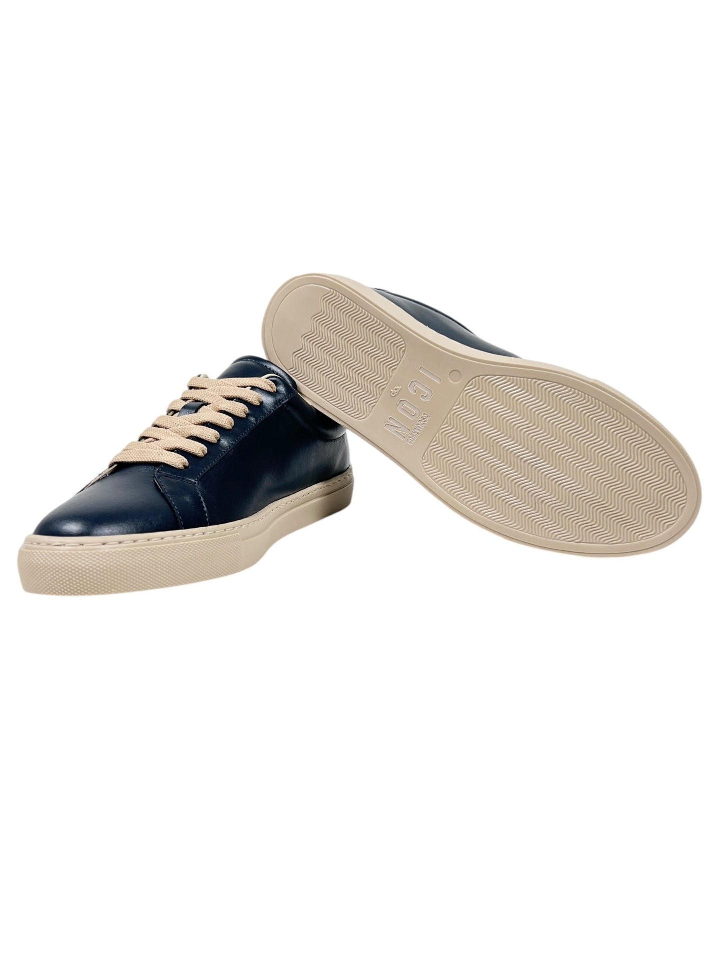 The DSQUARED2 SNM0384 Cassetta Sneakers in navy blue feature beige laces and soles, expertly crafted from premium leather, with one shoe standing upright and the other highlighting its textured sole.