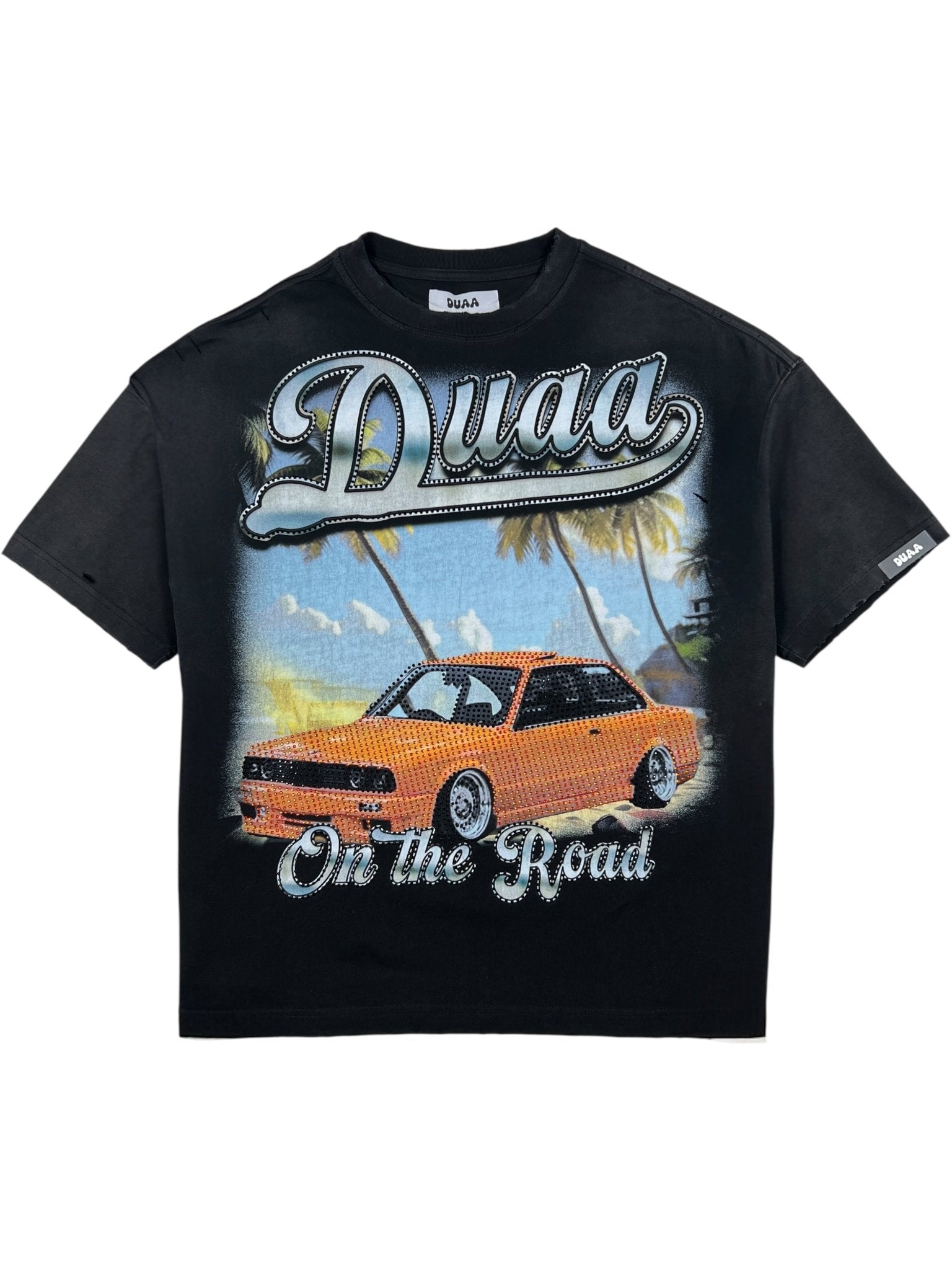 The DUAA Duaa Destination Blk Tee Shirt features "Duaa" and "On the Road" text with an orange sports car, palm trees, and a beach graphic—perfect for adding summer vibes to your casual style.