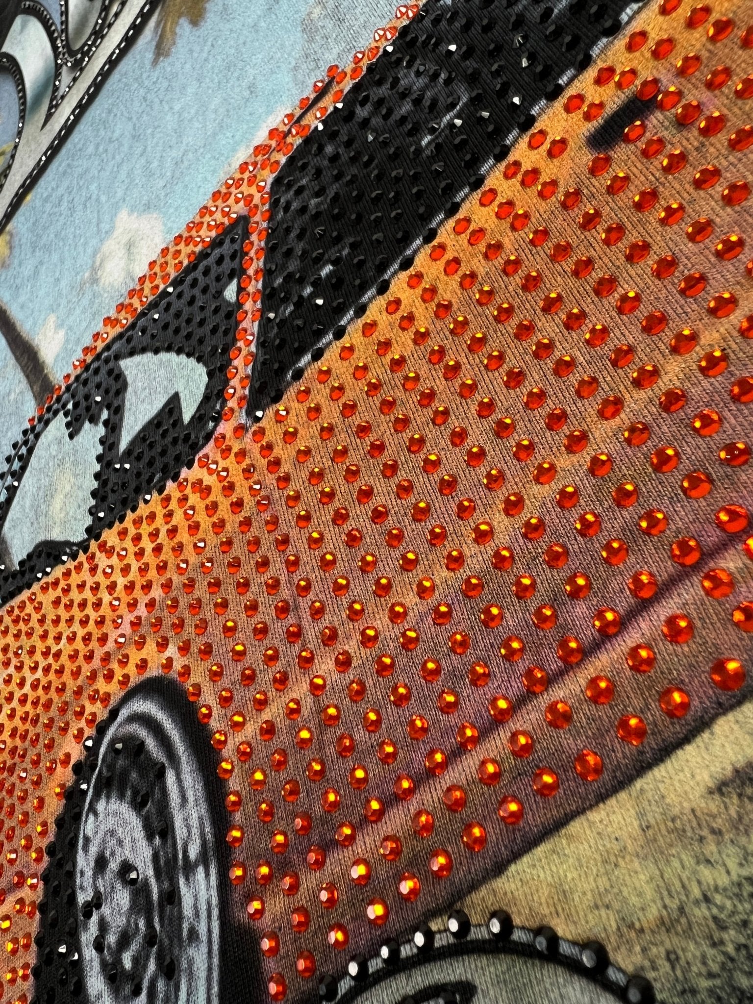 Close-up of DUAA Duaa Destination Blk Tee Shirt featuring an orange car illustration and evenly spaced, shiny red-orange crystal details.