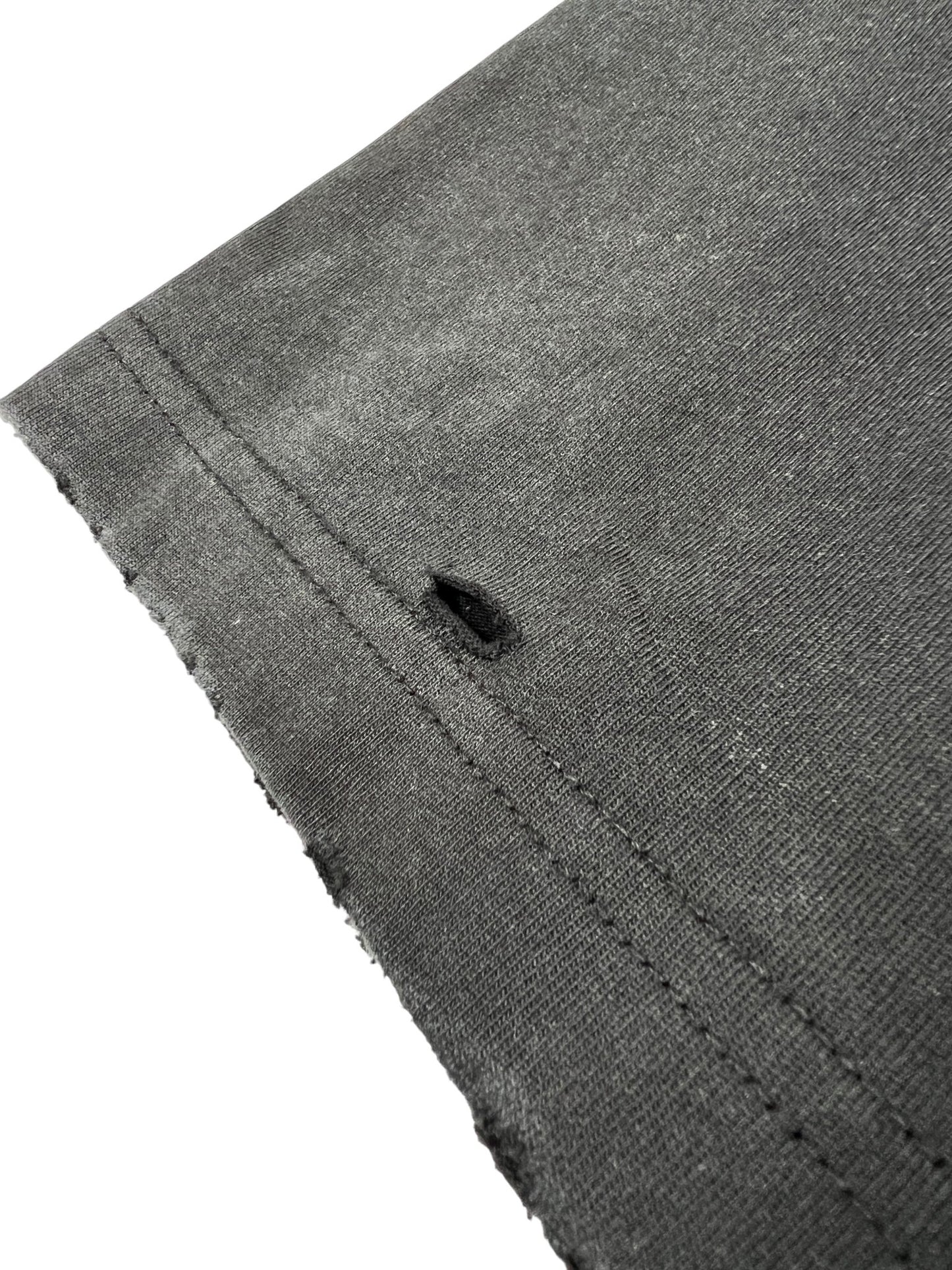 Close-up of a Duaa Destination Blk Tee Shirt by DUAA showing the edge with visible stitching and a small hole near the seam.
