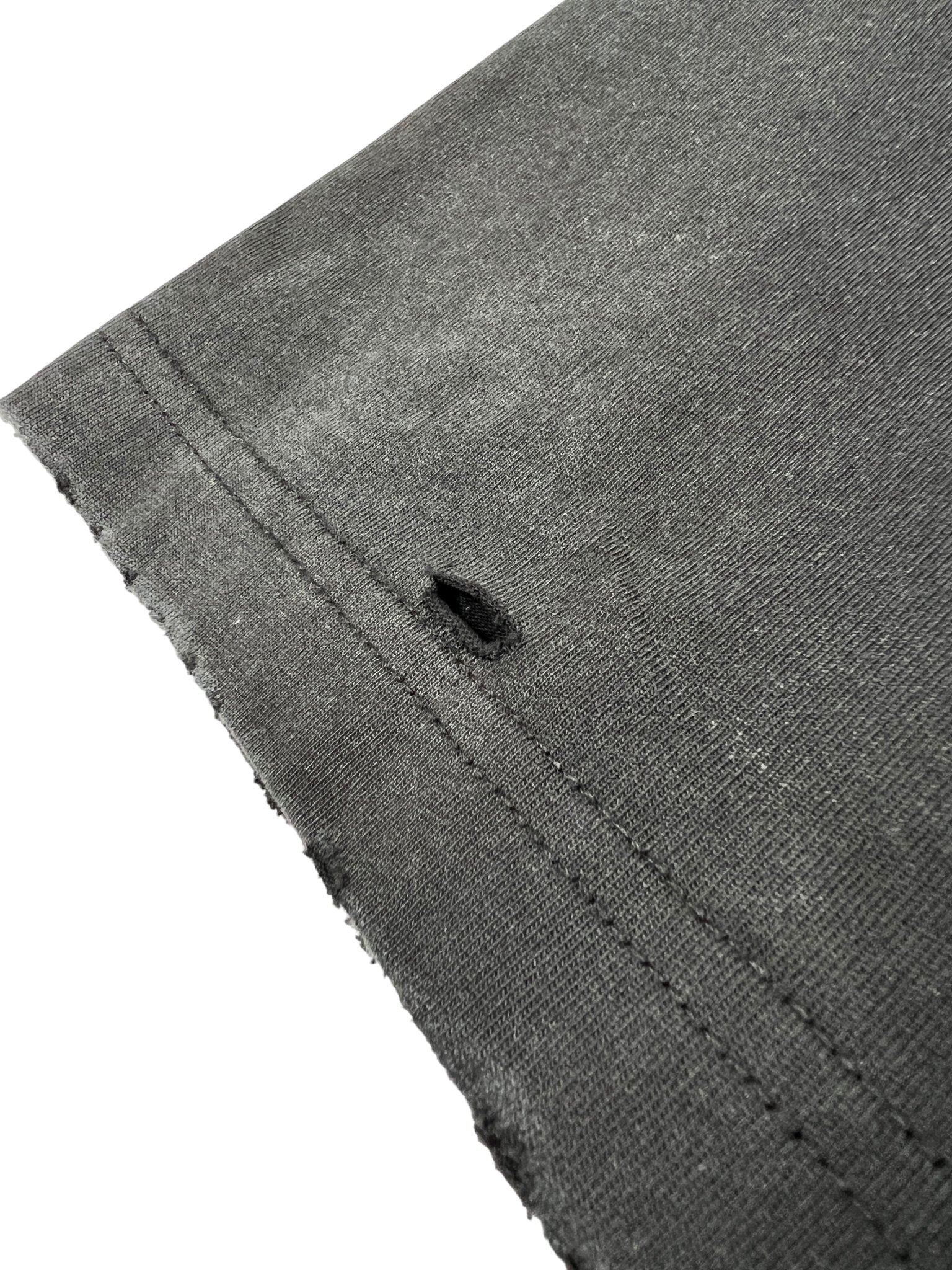 Close-up of a Duaa Destination Blk Tee Shirt by DUAA showing the edge with visible stitching and a small hole near the seam.