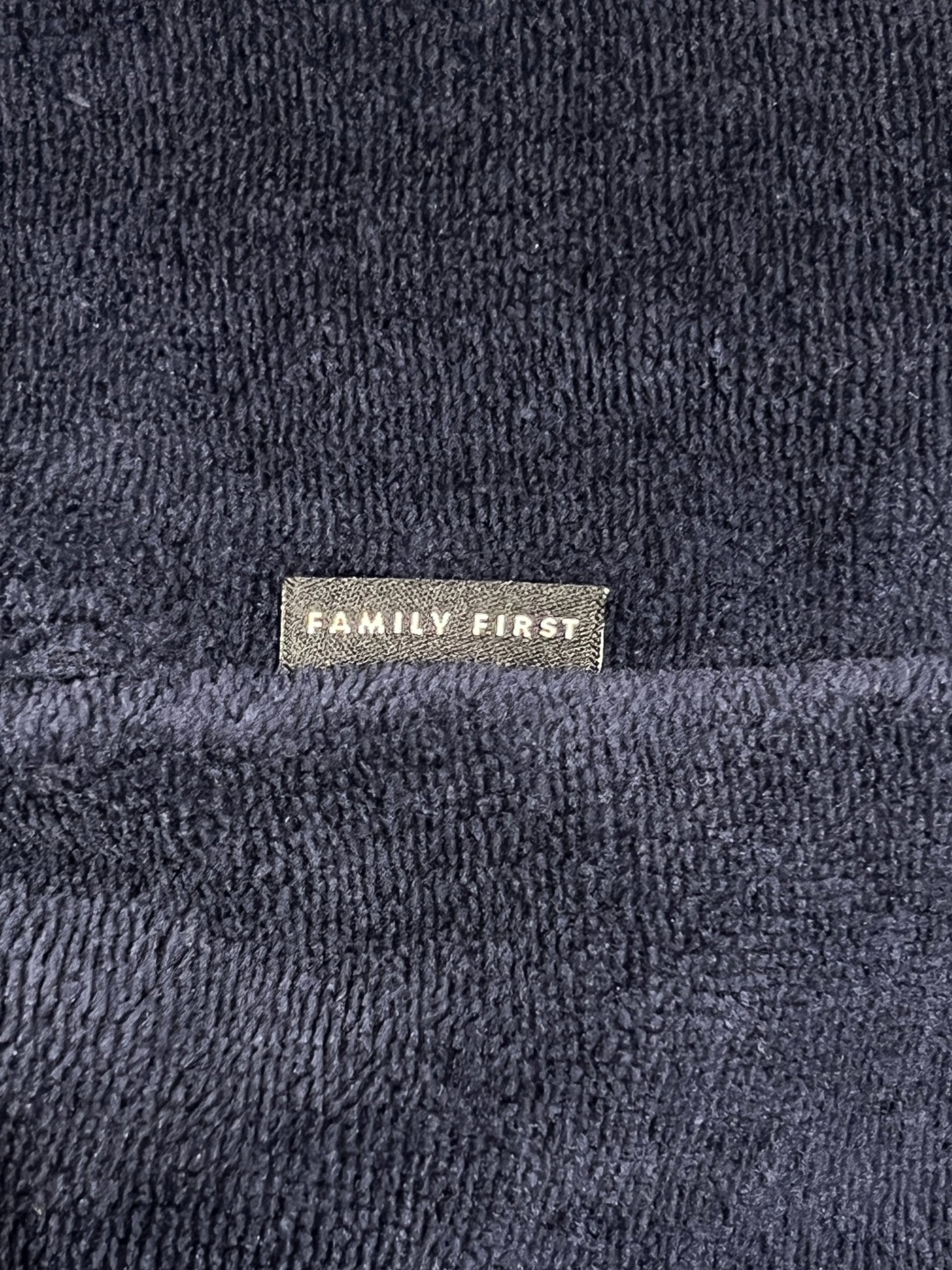 Close-up of textured dark blue jogger shorts labeled "FAMILY FIRST" in white text, from the Family First JOSS2504 collection.