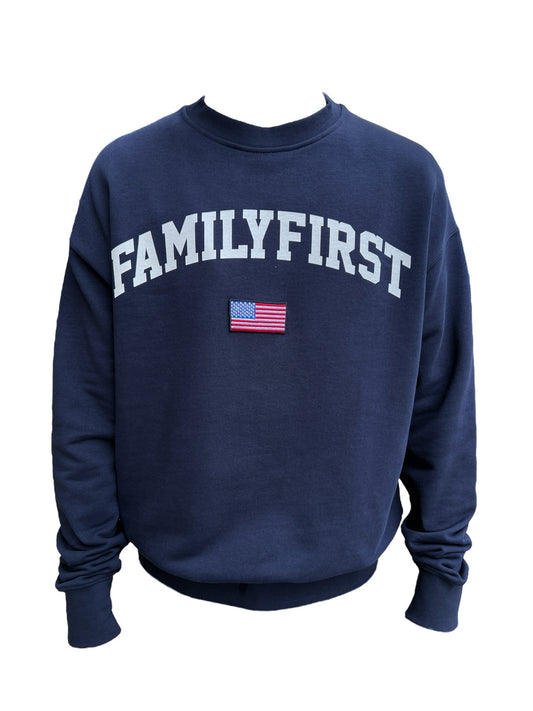 Navy blue FAMILY FIRST SS2402 CREWNECK COLLEGE DB sweatshirt with the phrase "family first" in white block letters and a small American flag graphic centered above the text, displayed against a black background.