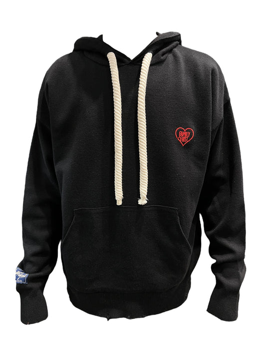 Sentence with replaced product name and brand name: FAMILY FIRST SWS2401 hoodie sweater in black with white drawstrings and a small embroidered heart logo on the left chest area, displayed against a black background.