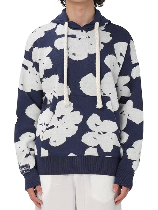 A person in a blue and white floral FAMILY FIRST SWS2405 HOODIE JAQUARD DB hoodie and white pants, torso and arms visible, against a plain background.