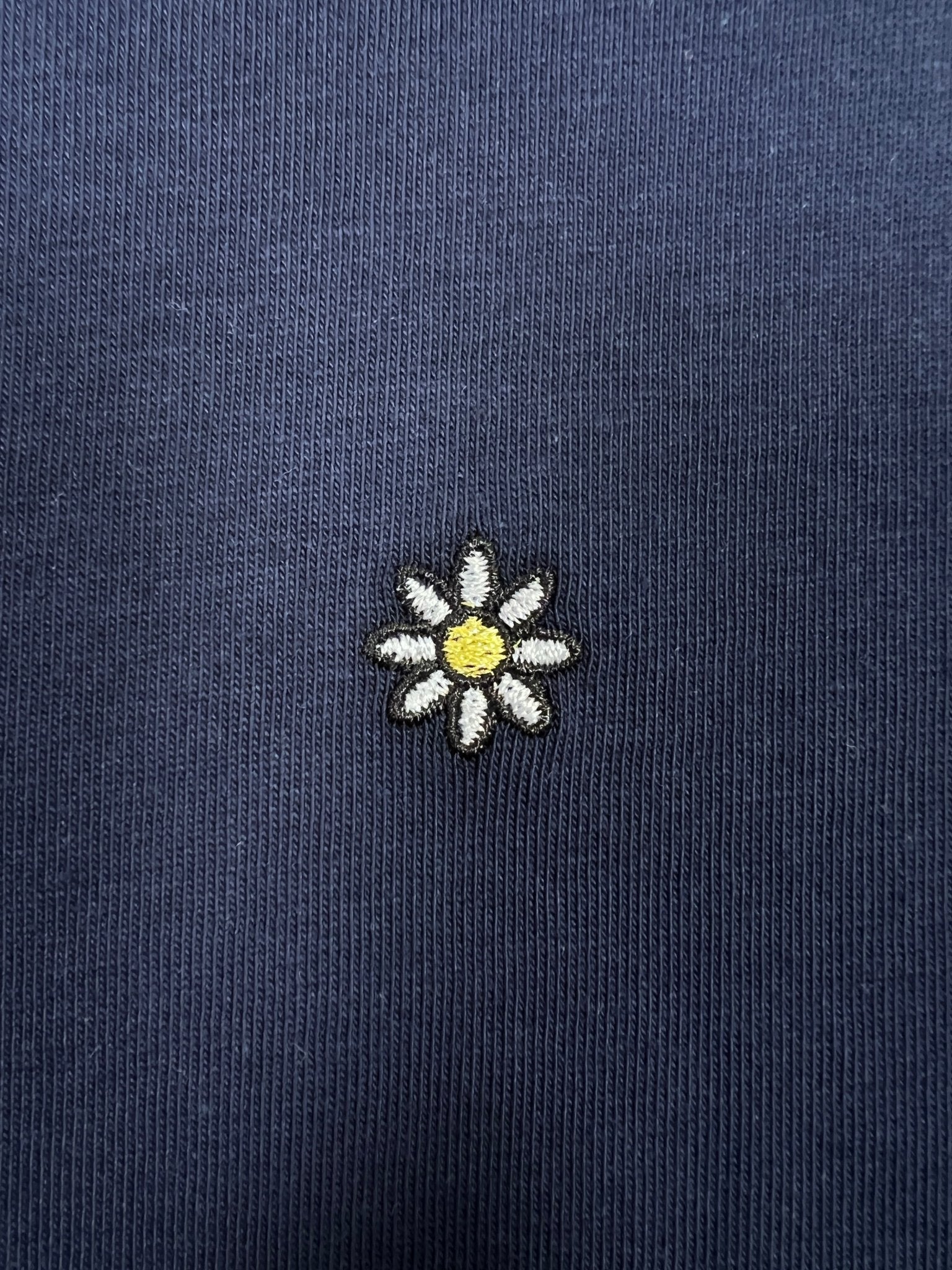 The Family First T2502DB T-shirt Flower Dark Blue by FAMILY FIRST features a charming embroidered daisy design on dark ribbed fabric, with white petals and a yellow center.