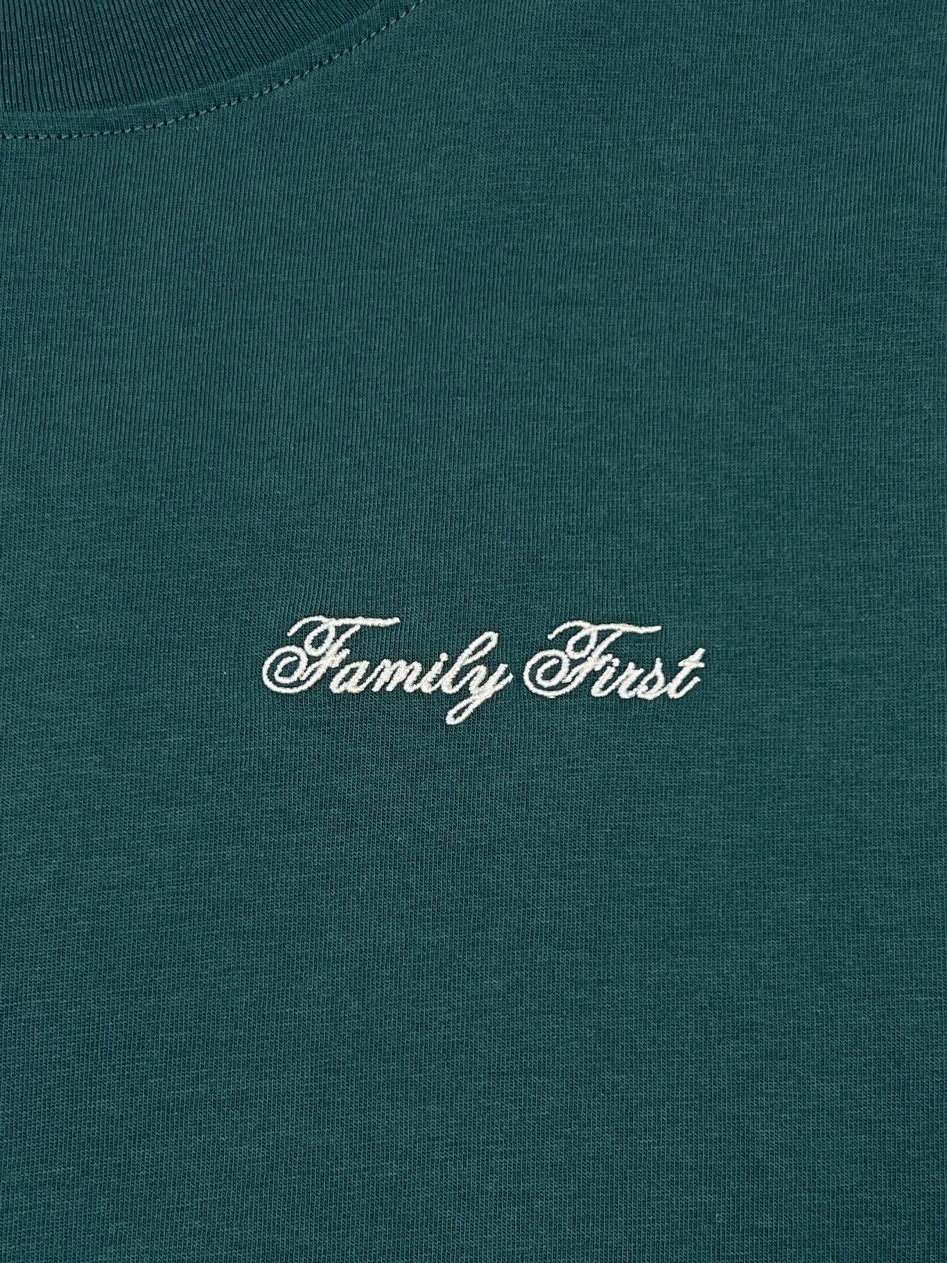 The Family First TF2409GR T-shirt Symbol Green features a luxurious green fabric with an elegant white cursive "Family First" embroidered logo.