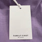 A white rectangular clothing tag with "FAMILY FIRST" is attached to the Family First TS2407 T-Shirt Swan Violet, characterized by its Italian elegance and digital print.