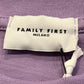 A white clothing tag with "FAMILY FIRST" in black text is sewn onto the violet fabric of the Family First TS2407 T-Shirt, capturing a sense of Italian elegance.