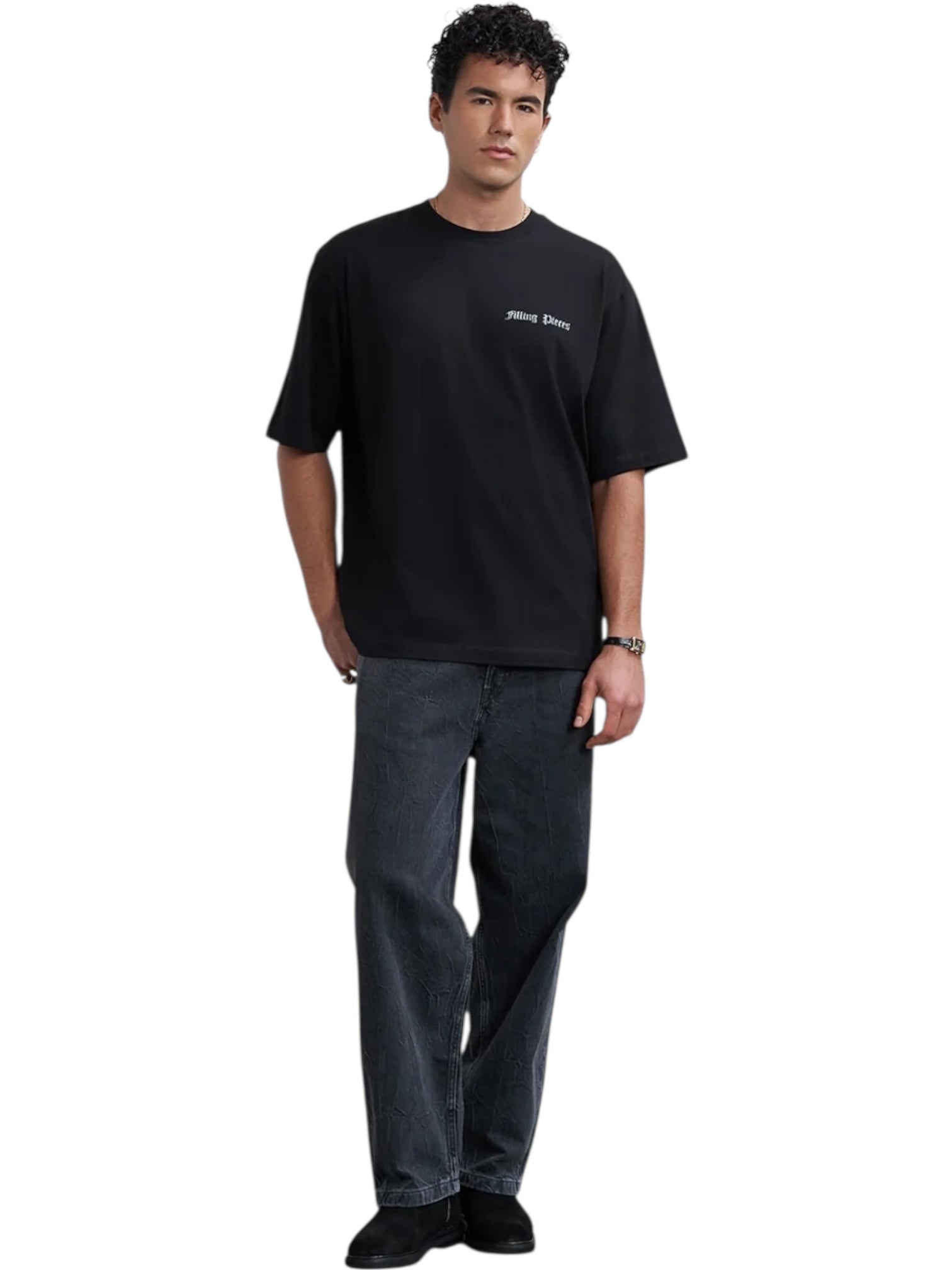 A man wears the FILLING PIECES Chrome Flower T-shirt in black—an organic cotton tee with white chest text—styled with dark jeans, black shoes, and a watch against a plain white background.