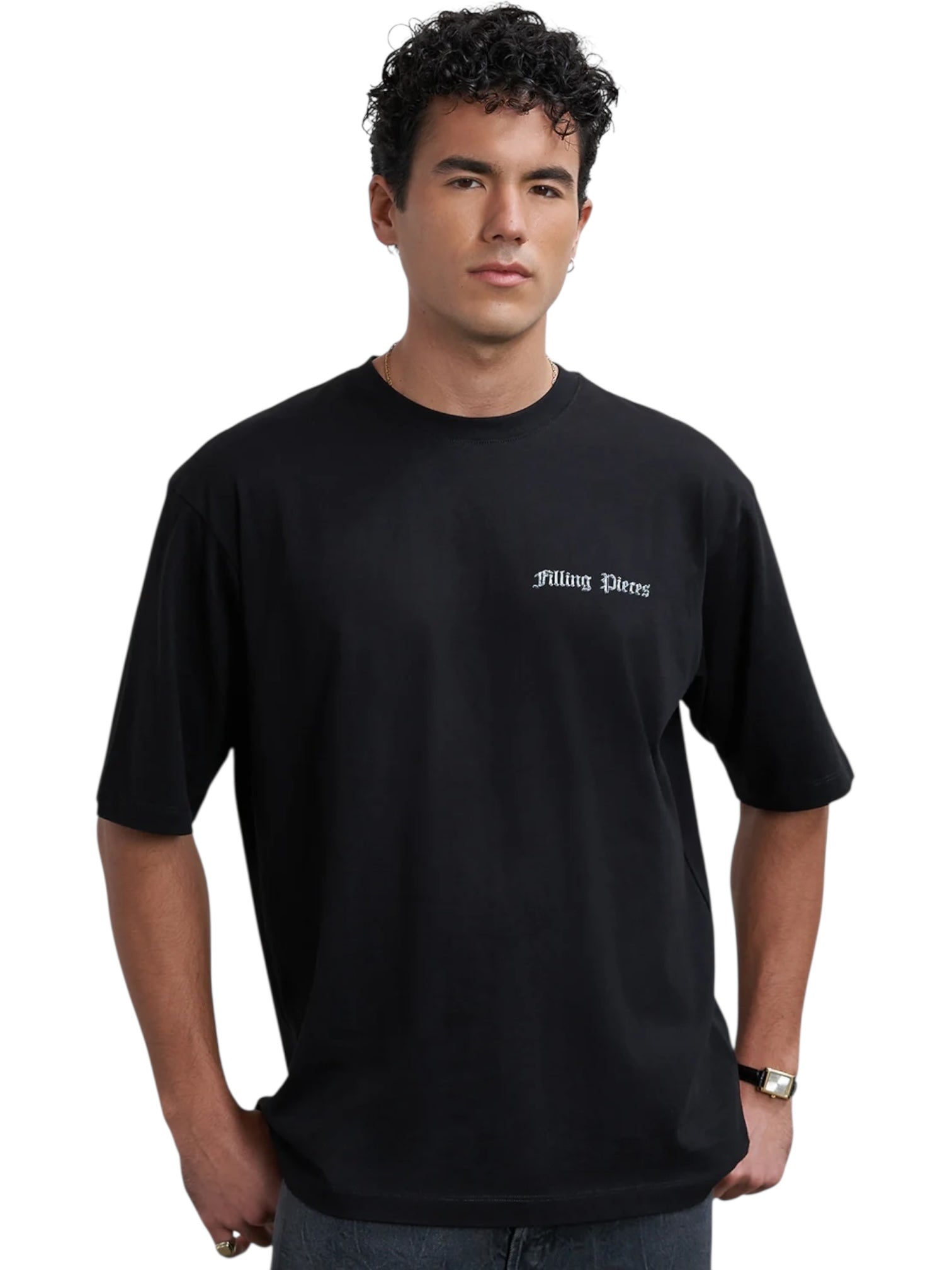 A person wears the Filling Pieces Chrome Flower T-shirt Black by FILLING PIECES, featuring a loose organic cotton fit and "Filling Pieces" printed on the left chest, standing against a white background.