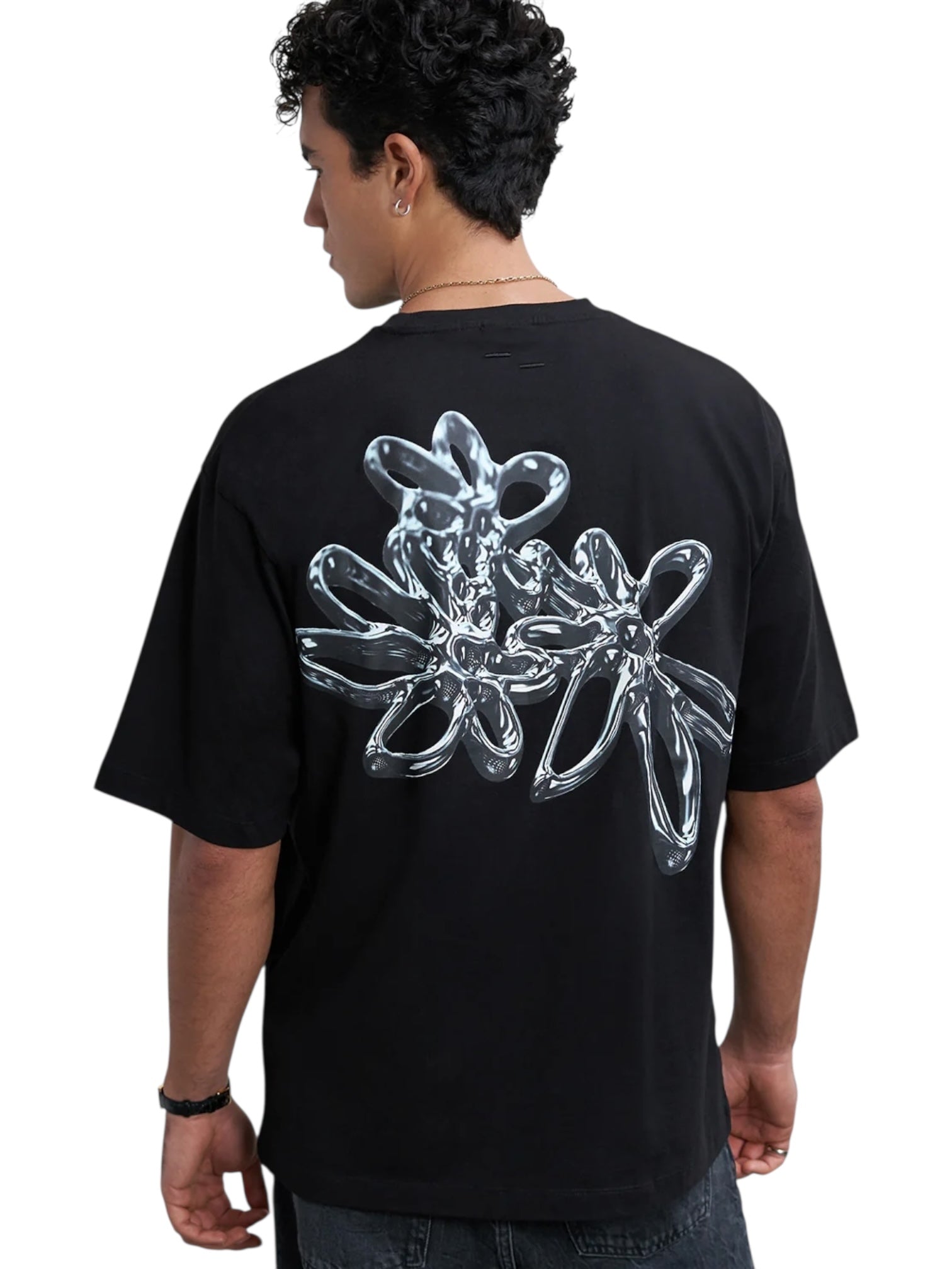 Someone seen from behind wearing the Filling Pieces Chrome Flower T-shirt Black by FILLING PIECES, featuring a large chrome flower design on the back.