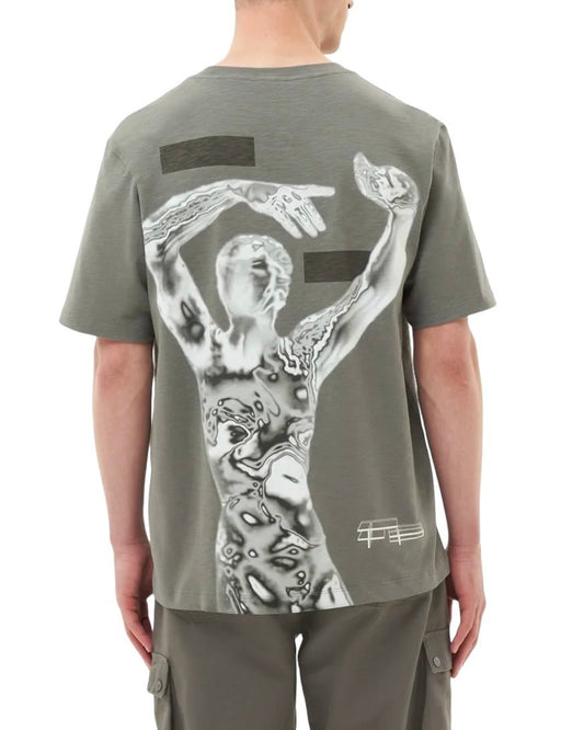 A person facing away, wearing the FILLING PIECES CHROME T-SHIRT GUN METAL made of 100% organic cotton with an abstract, monochrome graphic design of a person on the elevated backprint, and grey cargo pants.