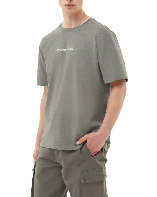 Person wearing a loose-fitting FILLING PIECES CHROME T-SHIRT GUN METAL made from organic cotton and gray cargo pants, standing with one hand in the pants pocket showcasing a fashion-forward look.