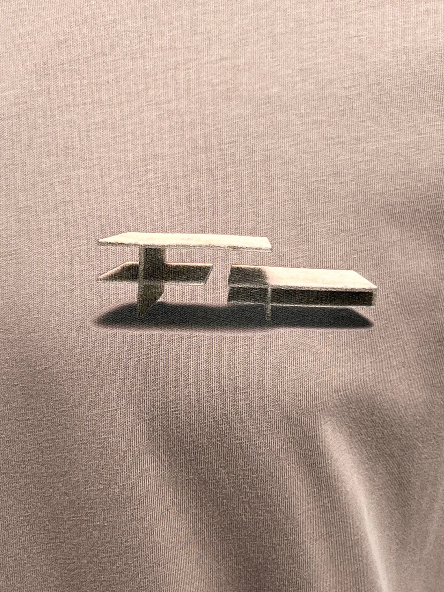 Close-up of a minimalist, abstract design featuring two layered, horizontal bars on a textured, grey background, ideal for the Filling Pieces Construct Fossil T-shirt crafted from organic cotton.