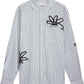 The FILLING PIECES Dress Shirt Flowers Antique White features blue vertical stripes and black abstract floral designs, blending modern style with subtle monogram detail for a distinctive look.