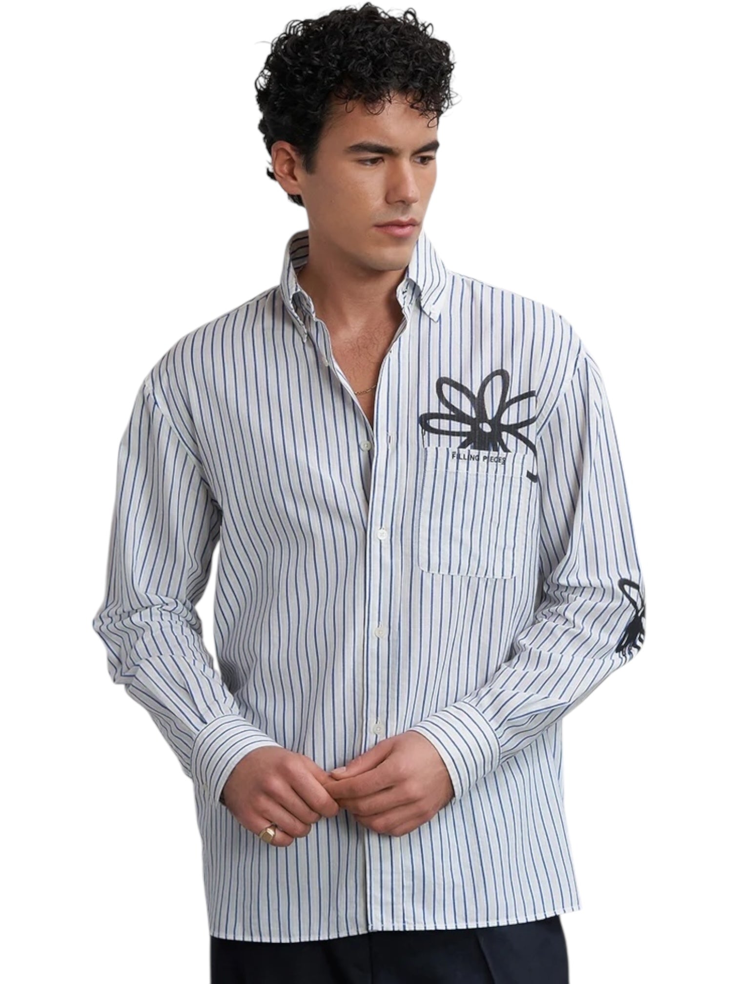 A man wears the FILLING PIECES Dress Shirt Flowers Antique White, featuring vertical blue stripes and black floral monogram patterns on the chest and sleeve against an antique white background.