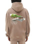 A person in the Filling Pieces Hoodie Pavilion Fossil by FILLING PIECES displays a modern house and trees illustration on the back of their beige organic cotton hoodie.