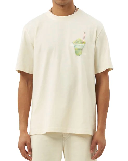 A person wearing a FILLING PIECES ICE VENDOR ANTIQUE WHITE t-shirt made of organic cotton, with a graphic of a green smoothie in a plastic cup printed on the front.