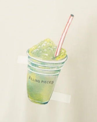 Illustration of a green slushie in a clear cup with a red straw, labeled "FILLING PIECES" on an organic cotton graphic jersey.