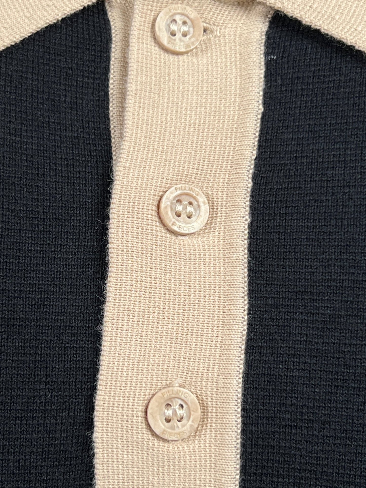 Close-up of a beige and black FILLING PIECES KNIT POLO BLACK featuring three FP branded beige buttons down the center, made from 100% cotton.