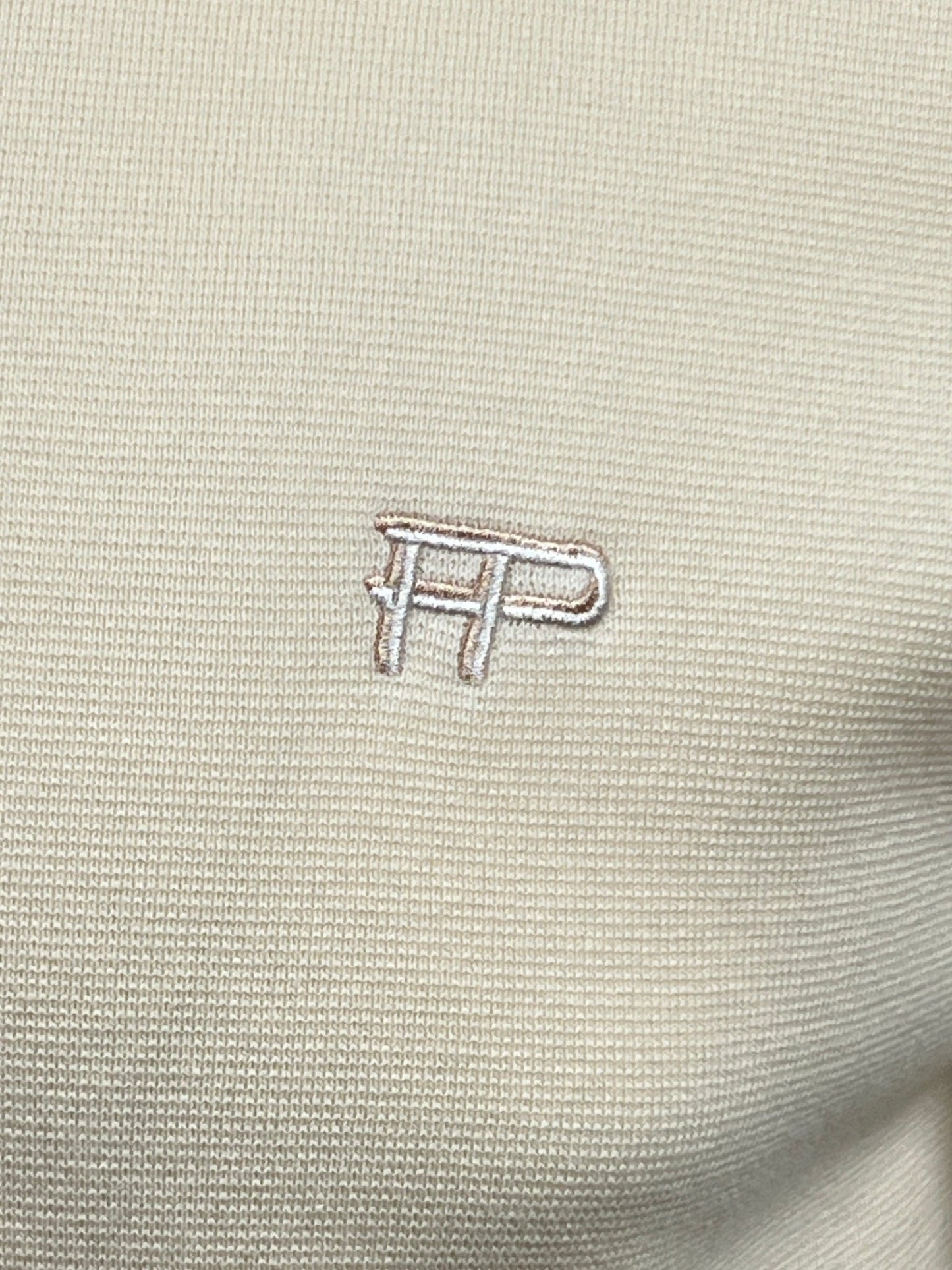 Close-up of the FILLING PIECES logo embroidered on a beige, 100% cotton Filling Pieces Knit Polo in Rice Brown.