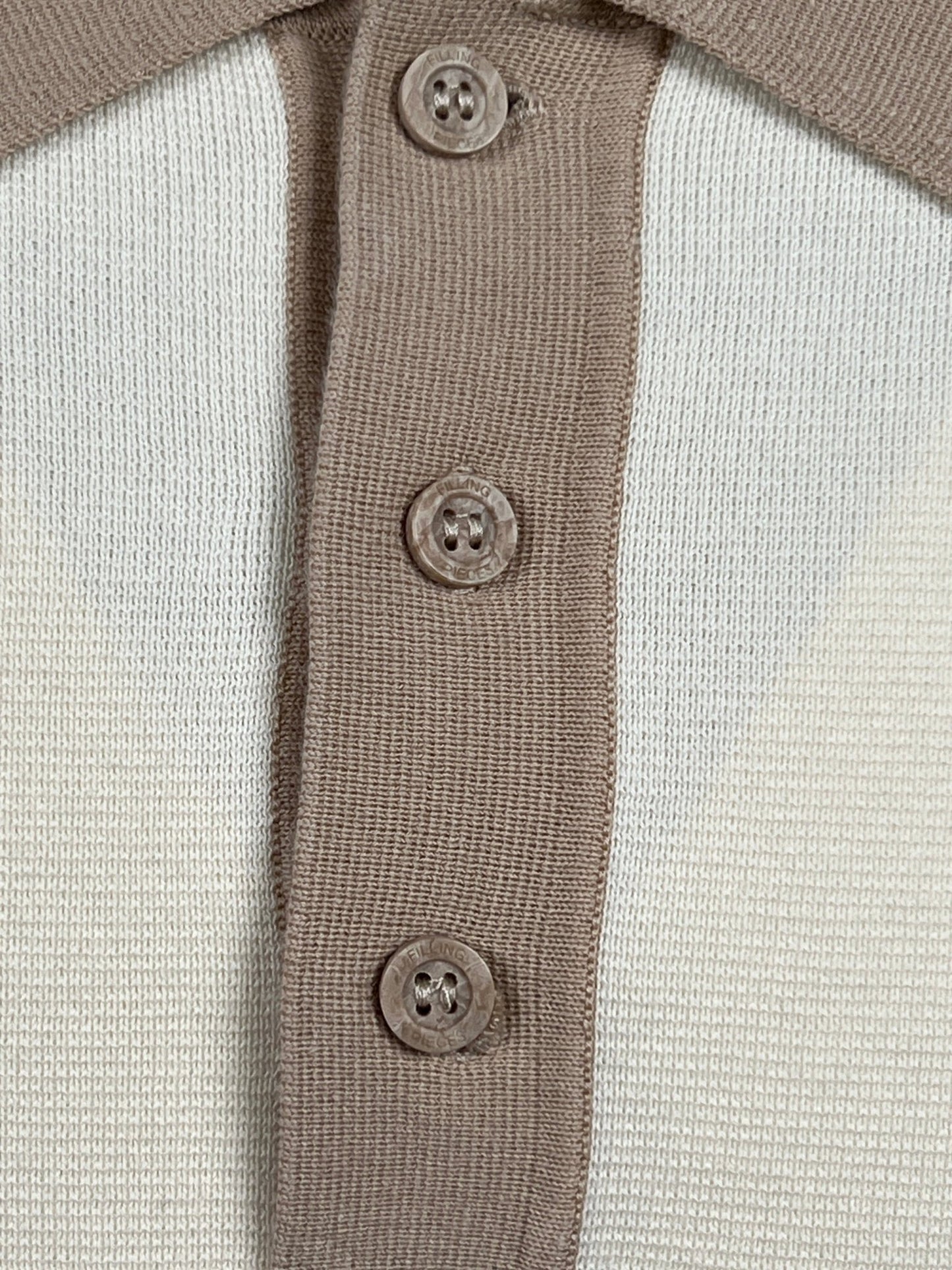 Close-up of a FILLING PIECES KNIT POLO RICE BROWN collar featuring three branded FP buttons. The fabric is made from 100% cotton, and the buttons are evenly spaced along the vertical placket. The shirt showcases a two-toned design with shades of beige and off-white.