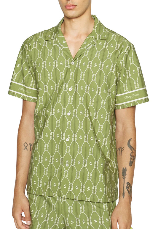 A man wearing a FILLING PIECES RESORT MONOGRAM SHIRT OLIVE made of 100% organic cotton with visible tattoos on his arms.
