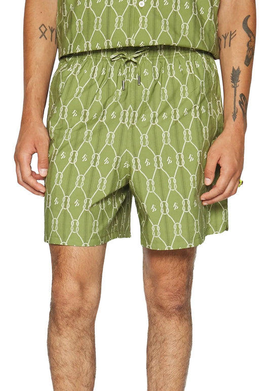A person wearing FILLING PIECES RESORT MONOGRAM SHORTS in olive green standing against a white background.