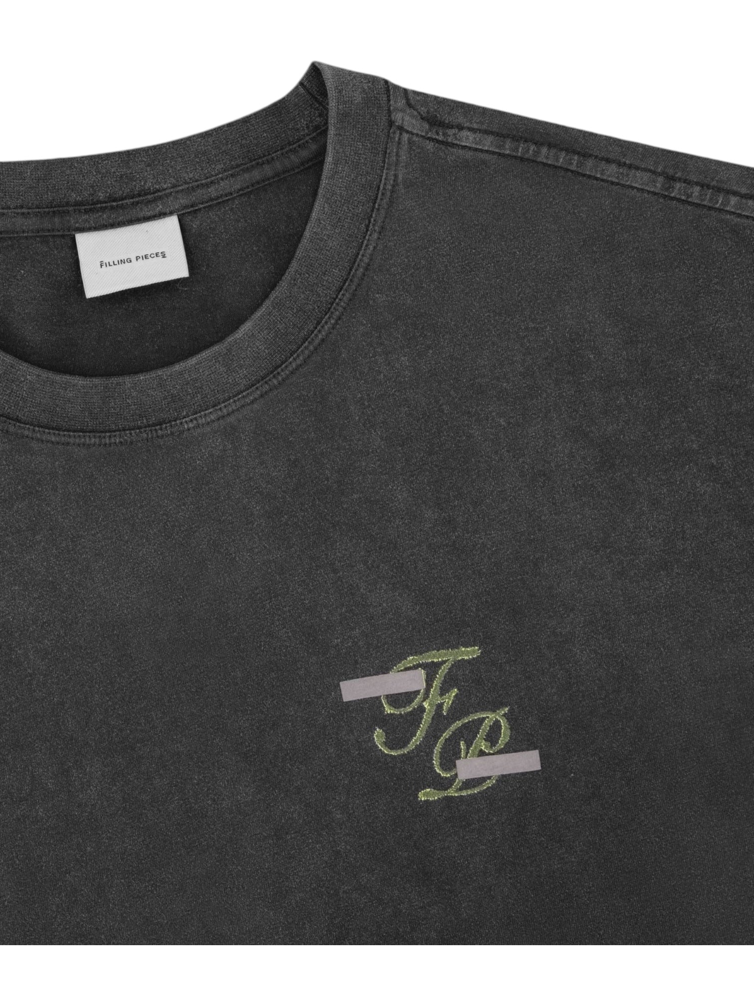 A close-up of the Filling Pieces Topiary T-shirt in vintage black by FILLING PIECES, featuring a small stylized "FP" logo with two gray lines on the left chest and an inner "Filling Pieces" collar label, made from soft organic cotton.