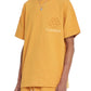 Someone shows off the Flaneur Flower Doodle T-Shirt Org by FLANEUR, a mustard yellow cotton jersey boasting the "FLÂNEUR" text and an adorable flower doodle graphic, perfectly paired with matching pants.