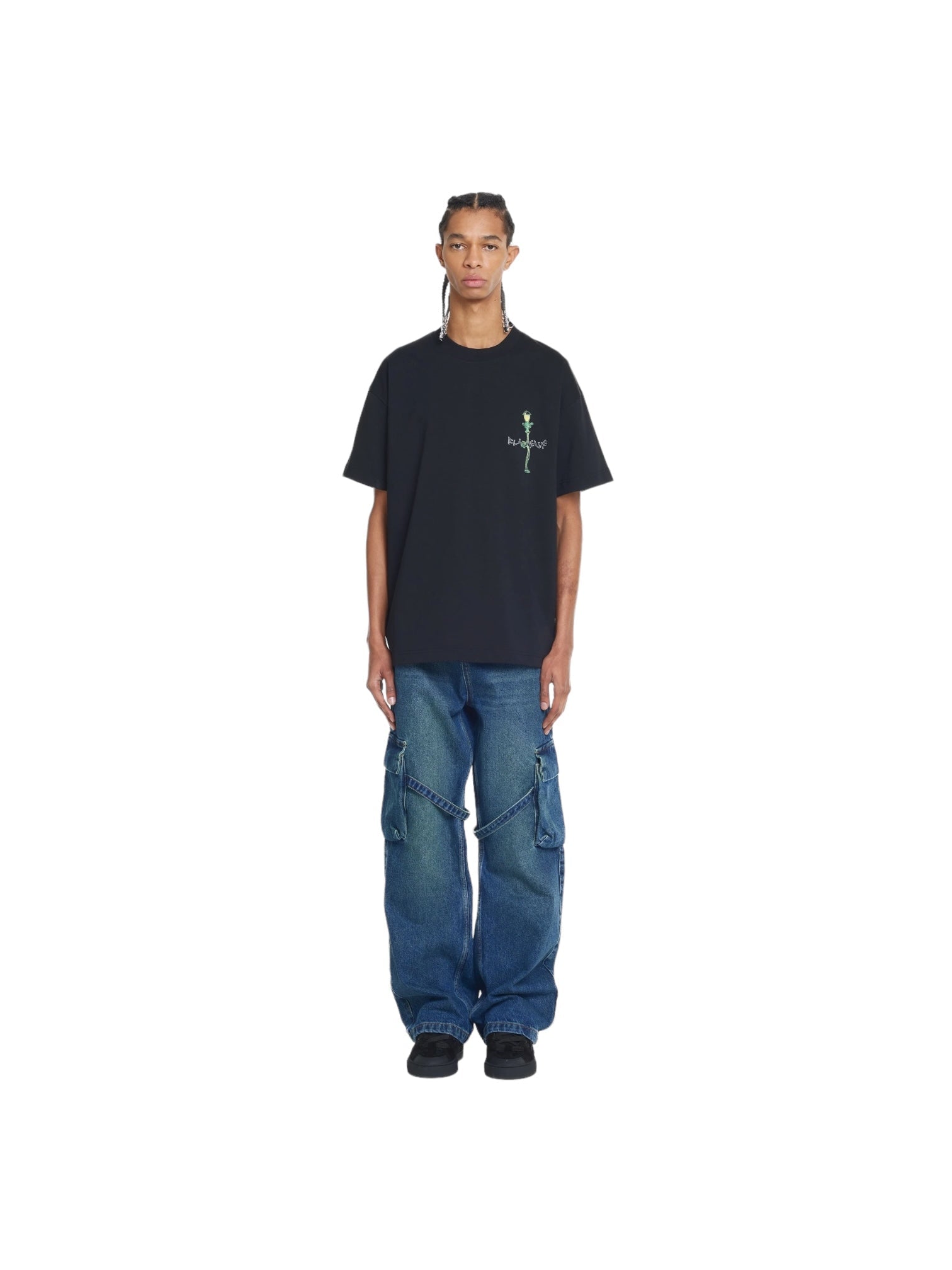 The person wears a FLANEUR Lantern T-Shirt in black and baggy blue jeans. This 100% cotton attire stands out against the crisp white background, exuding a laid-back charm.