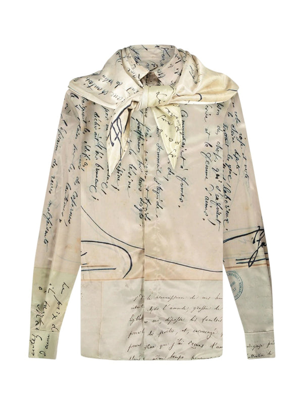 A long-sleeved viscose Letter Shirt by FLANEUR, showcasing a hand-written letter pattern and a tied bow at the neck. The fabric predominantly appears in beige neutral tones.